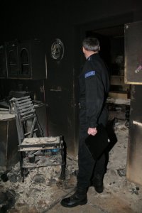 policjant wykonujący czynności na spalonym mieszkaniu