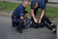 policjanci z zatrzymanym mężczyzną przeszukują go