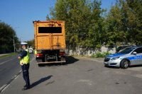 policjant z drogówki stoi na ulicy przy ciężarówce z odpadami i radiowozie