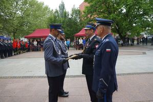 na zdjęciu wyróżnieniu policjanci otrzymują list gratulacyjny od komendanta straży w asyście komendanta Policji