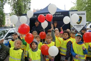 na zdjęciu dzieci z balonami z policjantem i strażniczką miejską