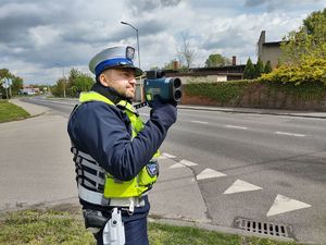 na zdjęciu policjant z radarem stoi przy drodze